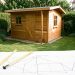 Petit abri de jardin compact en bois dans un jardin français, avec un mètre ruban et un plan d’implantation coté au premier plan.