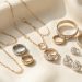 Collection élégante de bijoux variés disposés avec soin sur un tissu ivoire clair, éclairée par une lumière douce.