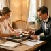 Un futur marié et une future mariée assis à une table en bois, écoutant des vinyles et préparant leur sélection musicale de mariage dans une lumière douce et élégante.